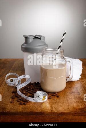 Coffee milkshake, ingredients, tape measure and shaker with paper straw on a wooden work top Stock Photo