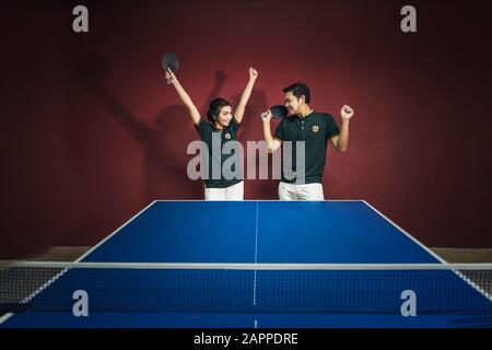 Couples of young people playing ping pong with ping pong paddles having fun Stock Photo