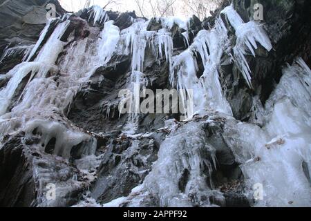 Large icicles covering rocky slope Stock Photo