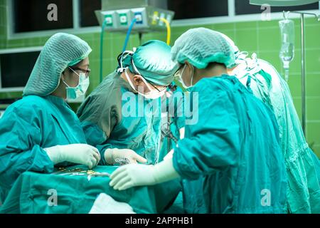 Group of surgeons at work operating in surgical theatre. Resuscitation medicine team wearing protective masks holding steel medical tools saving patie Stock Photo