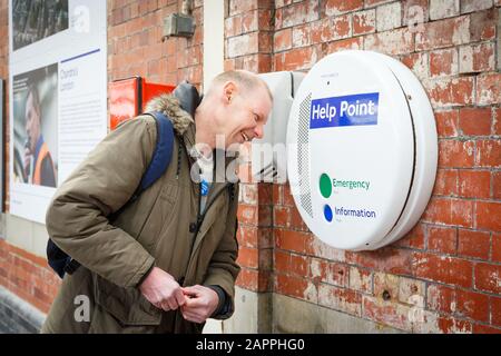 A passenger asks for help using a Help Point on the London Underground Stock Photo