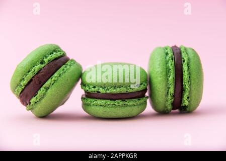 Three green tasty french macarons on a pink pastel background. Close-up. Place for text Stock Photo