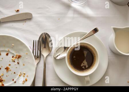 Cup of coffee, milk pot and empty plate on table Stock Photo