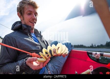 Climber playing with potato twister on portaledge against flaring sun, Squamish, British Columbia, Canada Stock Photo