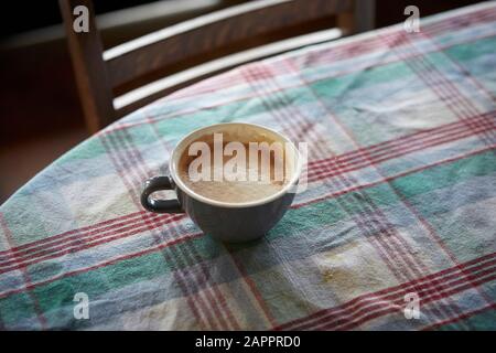 Cup of coffee on table covered with checkered cloth Stock Photo