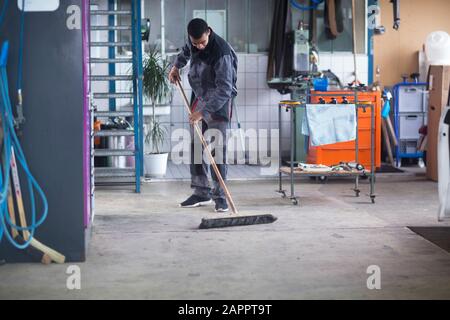 Workman cleaning floor in workshop Stock Photo