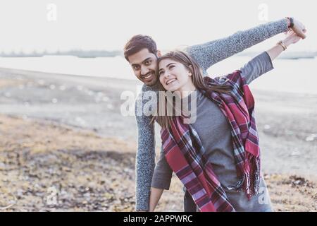 Happy young joyful couple having beach fun moments laughing together in autumn season with place for text Stock Photo