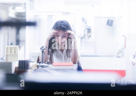 Asian woman in deep thought in technical office Stock Photo