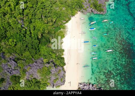 Tropical island with sandy with tourists and blue sea, aerial view. Matukad Island, Caramoan Islands, Philippines. Boats and tourists on the beach. Summer and travel vacation concept. Stock Photo