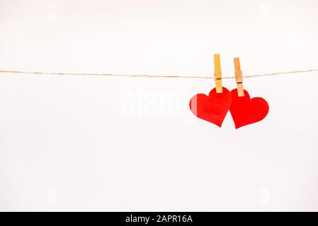 Clothes pegs and two red paper hearts on rope isolated on white background. Valentines day concept Stock Photo