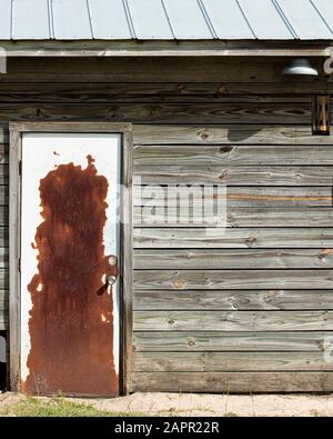 Old barn with rusty door and tin roof.  Wooden siding.  Barn light. Stock Photo