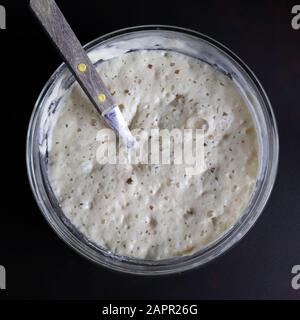 Cooking process. Top view of bowl with dough leaven. Preparing yeast dough for buns, pastries or pizza. Stock Photo