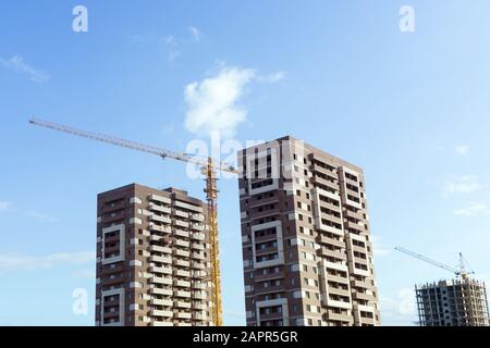 houses under construction against the blue sky. construction crane selective focus. free space for copy space. Construction of multi-storey buildings Stock Photo