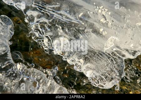 Transition from ice to water along a little forest creek in central Norway Stock Photo
