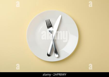 Plate with fork and knife on beige background, top view Stock Photo