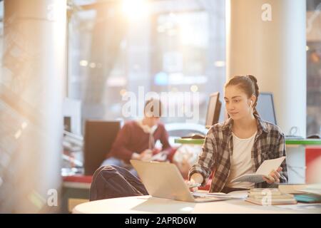 College student working online on laptop computer while sitting at desk in the library Stock Photo