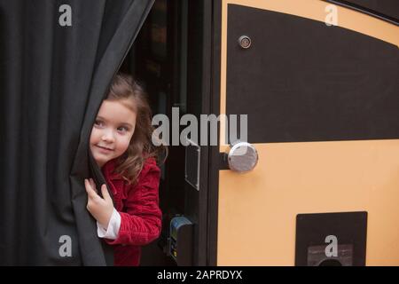 Young girl peeking out from a curtain Stock Photo