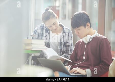 Two college students using laptop computer and reading books they preparing for exams together Stock Photo
