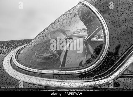 Grayscale shot of the front part of a car covered in raindrops Stock Photo