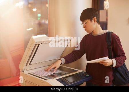 Asian college student making copy of new material using printer at university Stock Photo