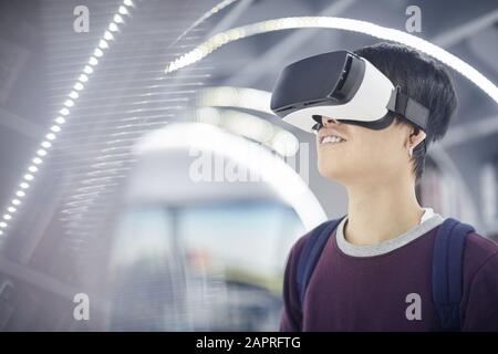 Young man with backpack behind his back wearing smart glasses and playing in video game Stock Photo