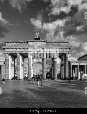 The Brandenburg Gate in Berlin, Germany, against a beautiful dramatic sky with some clouds in black and white Stock Photo