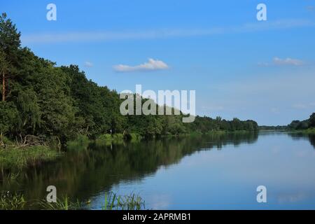 Big beautiful river, blue sky in summer, forested banks against the blue sky. European Sunny summer. Rest on the river Bank in a tent. Stock Photo