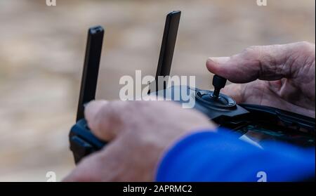 Close-up of an old man with his finger on the joystick operating a drone using a remote control Stock Photo