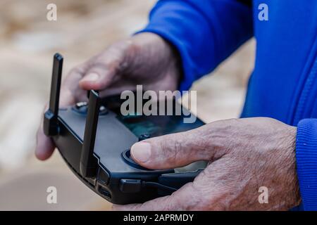 Close-up of an old man with his finger on the joystick operating a drone using a remote control Stock Photo