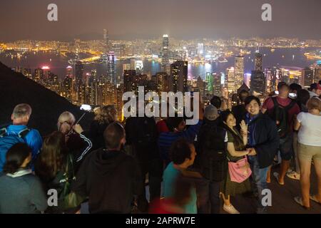 Hong Kong travel; Hong Kong tourists; people at the Peak, looking at the cityscape skyline view of the city at night, Hong Kong Asia Stock Photo