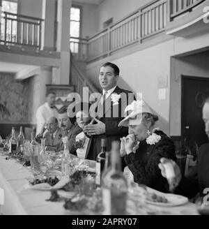 Wedding  A man with a corsage holds a speech during a dinner Date: May 10, 1932 Location: France Keywords: parties, bottles, guests, glass, fences, headgear, catering, interiors, meals, restaurants, speeches Stock Photo
