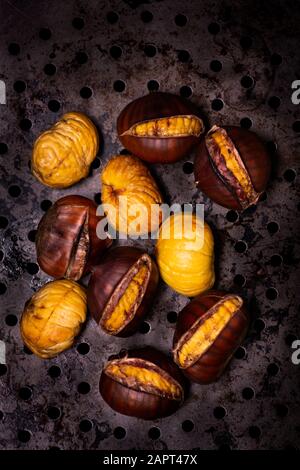 High angle view of some roasted chestnuts on the grill in the foreground Stock Photo