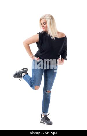 Vitality balance concept. Healthy playful middle age woman in fifties with casual clothes standing on one leg. Full body isolated on white background. Stock Photo