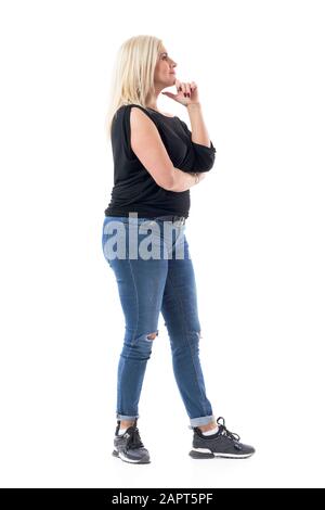 Profile view of interested casual middle aged woman looking up watching seminar with finger on chin. Full body length isolated on white background. Stock Photo