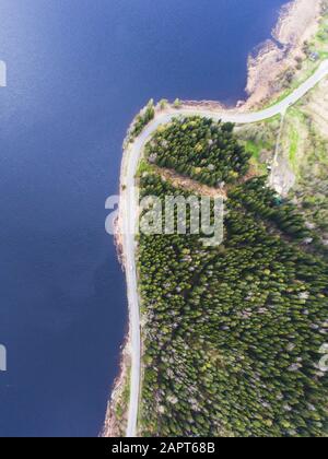 Beautiful view from a road going through the beautiful lake and forest, surrounded with water on both sides, shot above from drone, aerial vibrant pic Stock Photo