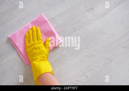 Cleaning concept in office, home. Female hand with pink rag is wipes light wooden floor at home. Housework and housekeeping concept. Stock Photo