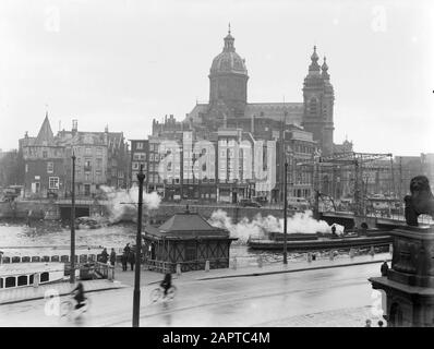 Reportage Amsterdam  View of the Prins Hendrikkade in Amsterdam with in the foreground the kiosk of the MijNederland Schellingwoude and in the background on the left the Schreierstoren and on the right the Sint Nicolas Church Date: 1933 Location: Amsterdam, Noord-Holland Keywords: churches, street images Stock Photo