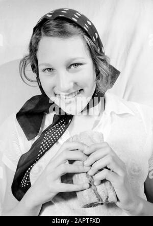 Family photos  Hans pose with kerchief, sandwich in hand Annotation: Regina (nickname Hans) was a stepdaughter of photographer Willem van de Poll Date: June 1936 Keywords: bread, headscarves, etc. portraits, women Stock Photo