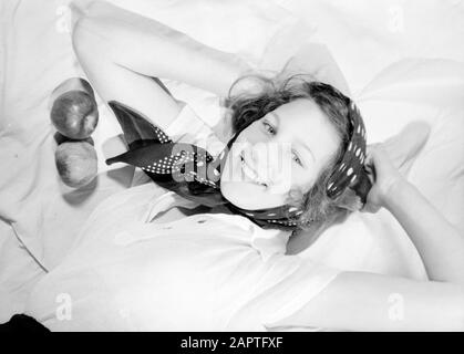 Family photos  Hans pose on bed with kerchief, next to two apples Annotation: Regina (nickname Hans) was a stepdaughter of photographer Willem van de Poll Date: June 1936 Keywords: apples, headscarves, portraits, women Stock Photo