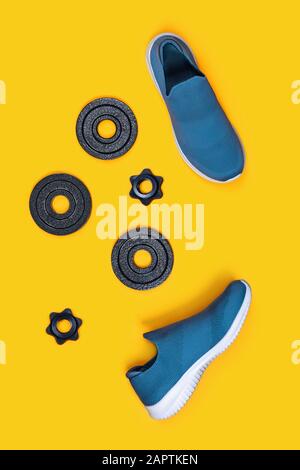 Sports vertical background. Dumbbells and Sneakers on yellow background. Flat lay, top view, copy space. Stock Photo