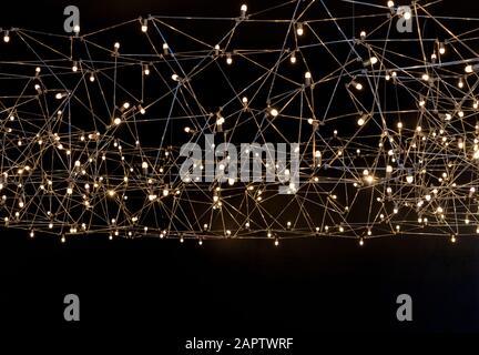 Ceiling lamp with small LED bulbs on a metal frame. Yellow garland on a black background. Stock Photo