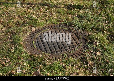 A metal sewer hatch in the grass Stock Photo