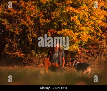 Woodlawn Cir and Opp Indian Hill St, East Hartford, CT 06108, USA - 11/04/2019. Enjoying the fall foliage, girl/teen/women plays catch with mini Aussi Stock Photo