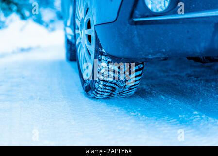 Winter tire on a vehicle on a snowy surface. Close-up Stock Photo