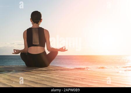 Young woman practicing yoga near the sea. Harmony and meditation concept. Healthy lifestyle Stock Photo