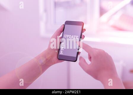 Conceptual hand writing showing Update. Concept meaning by adding new information or making corrections Up to date woman using smartphone and technolo Stock Photo