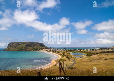 Stanley, Tasmania, Australia - December 15, 2009: Wide shot of The Nut volcanic plug and its surroundings under blue cloudscape.  Blue ocean, yellowis Stock Photo