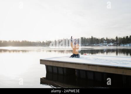 boy throwing snow up in the air whilst playing by the water in Sweden Stock Photo