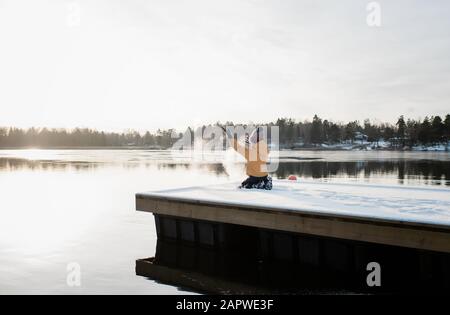 boy throwing snow up in the air whilst playing outside by Baltic sea Stock Photo