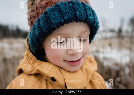 close up of a young boy looking down smiling whilst playing outside